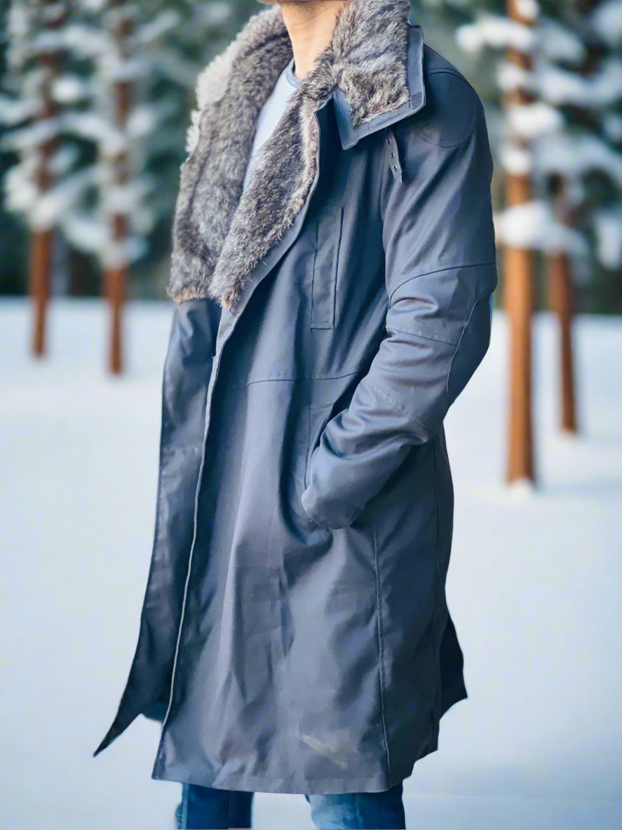Person wearing a long dark coat with a fur-lined hood in a snowy landscape