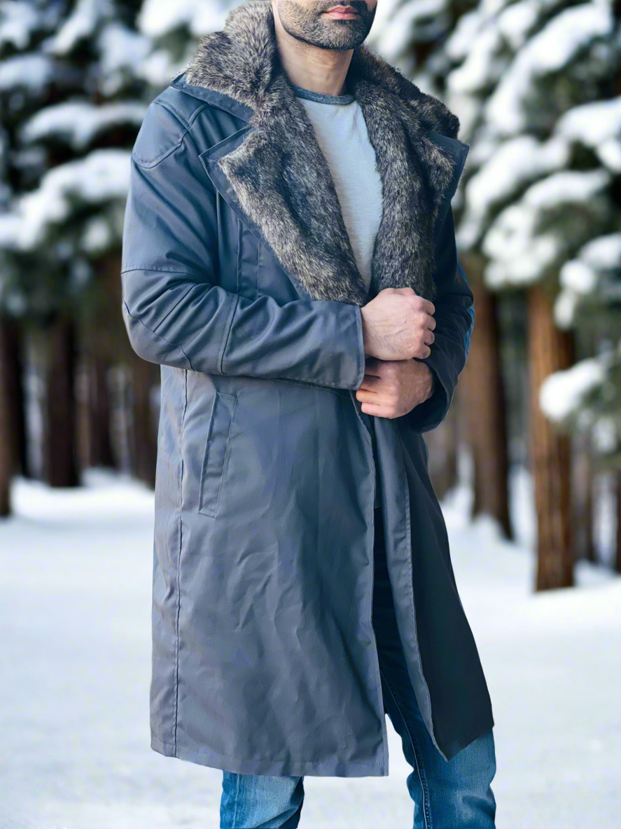 Man wearing a long coat with fur collar in a snowy forest setting